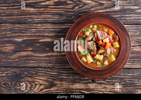 Di manzo caldo gulasch ungherese o bograch Zuppa servita in un vaso di argilla su un tavolo di legno, ricetta classica, vista da sopra Foto Stock