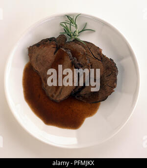 Piastra del manzo al Barolo fette di manzo marinato in salsa di vino rosso, guarnita con il rametto di rosmarino, un piatto tipico piemontese, vista da sopra Foto Stock