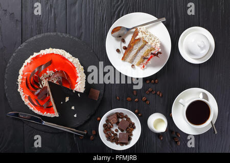 Porzione di deliziose torte con crema spuma di formaggio servita su tavoli in legno nero con tazza di caffè e crema, vista da sopra Foto Stock