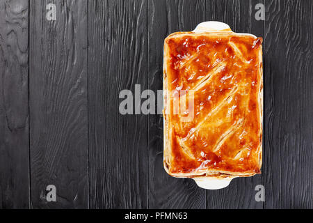 Deliziose Carni bovine e torta di Funghi Conditi con crosta dorata sfoglia di pasta sfoglia in una teglia sul tavolo di legno, ricetta australiana, vista da sopra Foto Stock