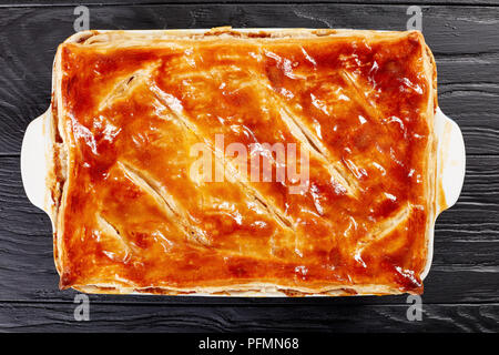 Deliziose Carni bovine e torta di Funghi Conditi con crosta dorata sfoglia di pasta sfoglia in una teglia sul tavolo di legno, ricetta australiana, vista da sopra, chiudi Foto Stock