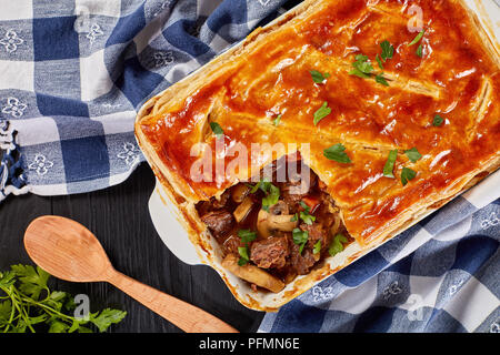 Deliziose Carni bovine e torta di Funghi Conditi con crosta dorata sfoglia di pasta sfoglia in una teglia sul tavolo di legno, ricetta australiana, vista da sopra, chiudi Foto Stock