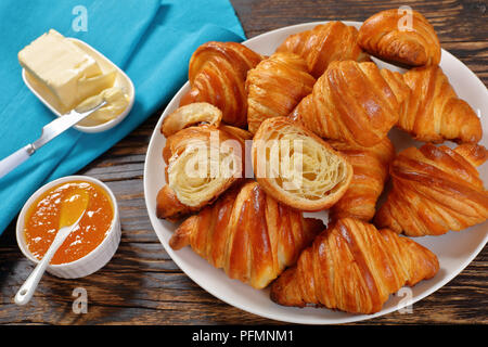 Close-up di deliziosa casa appena sfornato francese croccante croissant serviti per colazione sul piatto bianco con marmellata di albicocche e burro fresco sulla ruggine Foto Stock