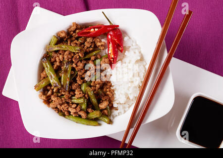 La carne di maiale Stir Fry con carbonizzati fagioli verde servito con riso e salsa di soia, ricetta cinese, vista da sopra, close up Foto Stock