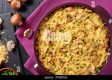 Tetrazzini - spaghetti, carne di pollame, formaggio grattugiato, piselli verdi, casseruola di funghi in una teglia da forno con ingredienti a sfondo, cucina americana Foto Stock