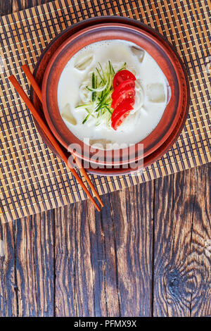 Kongguksu, Kong-guksu - deliziosa estate freddo coreano con zuppa di latte di soia e riso noodle e rabboccato con strisce di cetriolo e le fette di pomodoro, vista orizzontale Foto Stock