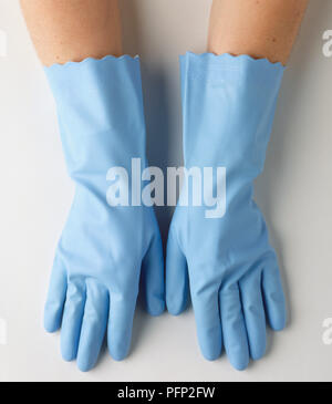 Le mani della persona che indossa un paio di blu guanti di gomma, vista dall'alto. Foto Stock