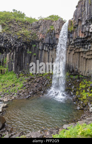 Una cascata in Islanda tra i monti dal fiume molla Foto Stock