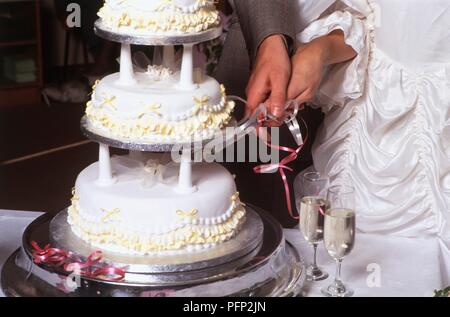 Sposa e lo sposo il taglio di torta di nozze, close-up Foto Stock