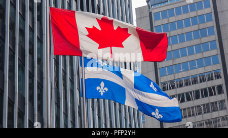 Il Quebec e del Canada bandiere svolazzanti nel vento insieme nel centro cittadino di Montreal. Foto Stock