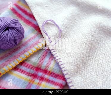 Maglie coperta la decorazione del bordo di un tessuto, sfera di lana di colore viola nelle vicinanze Foto Stock