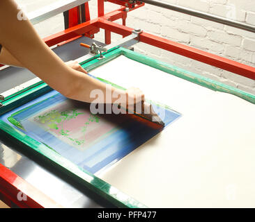 Tirando una spatola attraverso stencil per creare screenprint Foto Stock