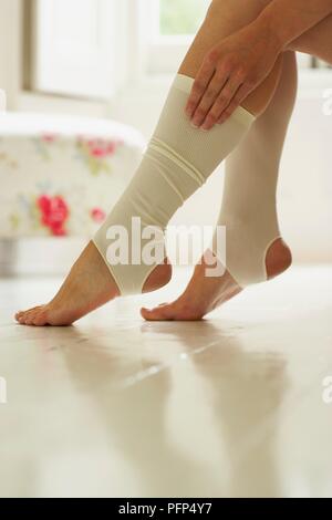 Close-up sulla donna di piedi e vitelli di indossare calze di maternità Foto Stock