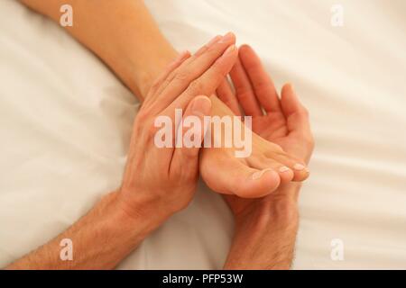 Mani dell'uomo massaggiando delicatamente una donna di cibo, close-up Foto Stock