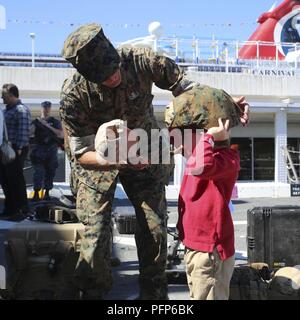 Un U.S. Marine con scopo speciale Air-Ground Marine Task Force Settimana della flotta New York aiuta un bambino regolare di un casco in kevlar per montare la sua testa a bordo della USS Arlington (24 LPD) durante la settimana della flotta di New York, 24 maggio 2018. Settimana della flotta di New York è una opportunità per il pubblico americano e per soddisfare le loro Marine Corps, la marina e la Guardia Costiera team e l'esperienza dell'America servizi di mare. Foto Stock