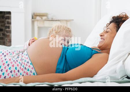 Incinta donna giaceva a letto con la ragazza spiata oltre il suo ventre Foto Stock