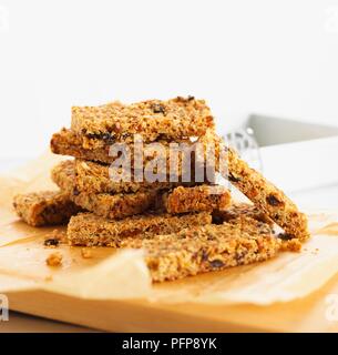 Pila di pane appena sfornato, avena e uvetta flapjacks sul tagliere Foto Stock