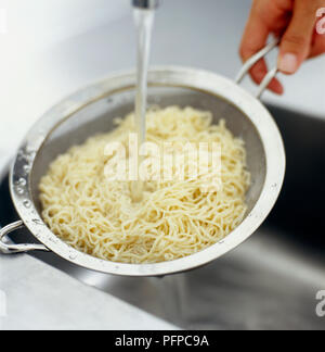 Tagliatelle rinfrescante nel setaccio sotto corrente di acqua fredda Foto Stock