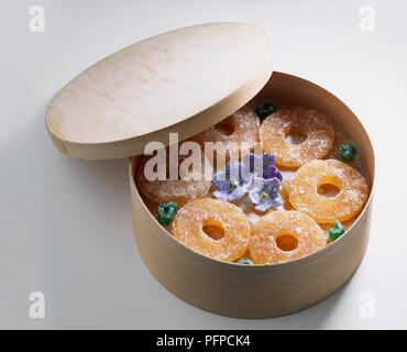 I canditi di anelli di ananas in scatola di legno con cristallizzato fiori viola Foto Stock