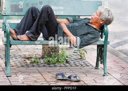 L'uomo addormentato sul banco, Bangkok, Thailandia Foto Stock