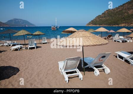 Turchia, sedie a sdraio e palapas sulla Adrasan beach, vicino a Kemer Foto Stock