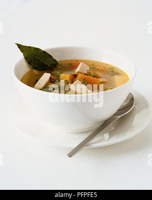 Ciotola di chunky minestra di verdura con zucca, semi di zucca, tofu, guarnite con foglie di alloro Foto Stock