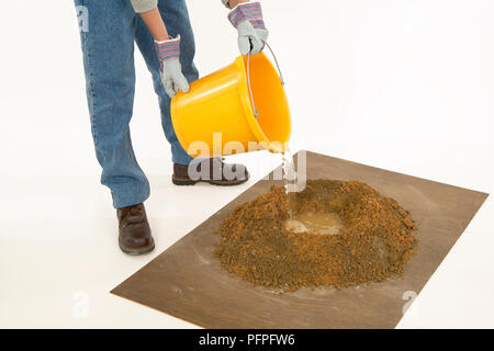 Versare acqua da una benna al centro del cemento secco mix Foto Stock