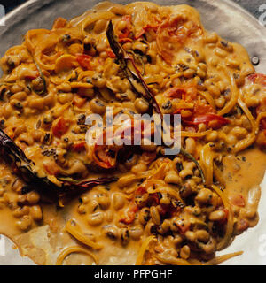 Lobia (fagioli neri) con crema di cipolle e tutto il peperoncino rosso sulla piastra di metallo, close-up Foto Stock