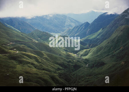 Il Vietnam, Sapa, Tram Ton Pass, le colline di valle lussureggiante con nuvole sopra le montagne sullo sfondo Foto Stock