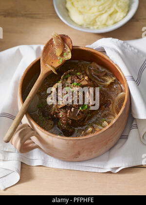 Carni bovine la pentola arrosto servita in terracotta casseruola con tazza di purea di patate, close-up Foto Stock