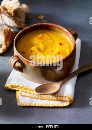 Zucca e zenzero zuppa con il cucchiaio di legno sul tovagliolo piegato sul tavolo, close-up Foto Stock