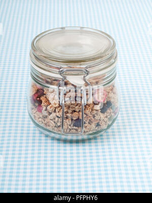 Muesli a tenuta Clip-top jar sul blu e bianco tovaglia controllati, close-up Foto Stock