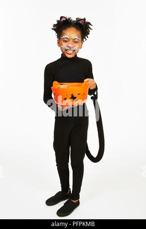 Bambino vestito da gatto nero con un trucco-o-trattare la benna Foto Stock