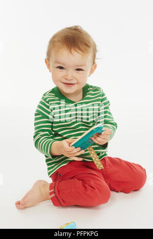Little Boy in verde stripey top inginocchiato (Modello età - 22 mesi) Foto Stock