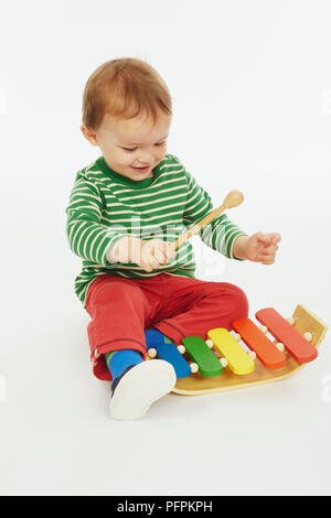 Little Boy in verde stripey inizio giocando con xilofono (Modello età - 22 mesi) Foto Stock