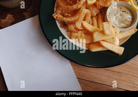 Su un bancone piastrellato nero vengono offerte porzioni di patatine fritte  con sopra formaggio e carne macinata di manzo t