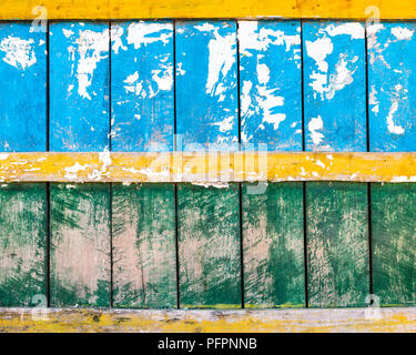 Grungy blu, verde e giallo parete in legno texture, la presenza di frammenti di carta nella metà superiore Foto Stock