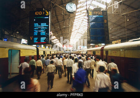 India, Mumbai, Churchgate Station, gente camminare lungo la piattaforma, i treni su entrambi i lati, vista posteriore Foto Stock