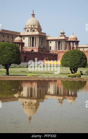 India, Delhi, Rajpath, blocco del nord, Segreteria della facciata del palazzo del governo riflessa nell'acqua al di sotto di Foto Stock