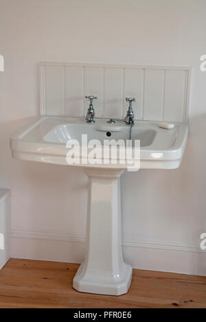 Bianco lucido il lavandino in bagno con pavimento in legno Foto Stock