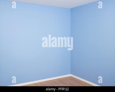 Stanza vuota con recentemente decorato pareti blu, bianco battiscopa e pavimento in legno Foto Stock