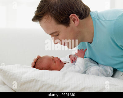 L'uomo sporgendoti baby boy (10 giorni), toccando delicatamente la testa del bambino Foto Stock