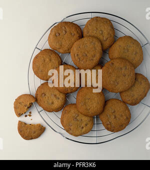 I biscotti al cioccolato a cottura e raffreddamento su una rastrelliera, uno è rotto in metà Foto Stock