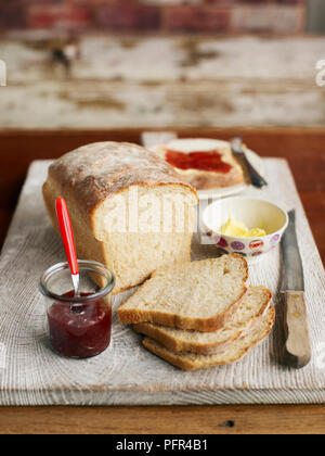 Pane a fette di pane sulla tavola di legno con marmellata e burro Foto Stock