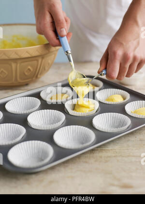 Spooning cupcake miscela in casi di carta Foto Stock