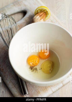 Uova, la senape e il succo di limone in un recipiente, frusta nelle vicinanze (ingredienti per la maionese) Foto Stock