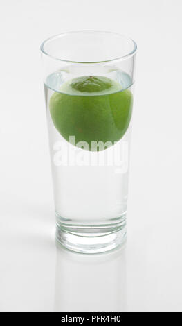 Lime galleggianti in un bicchiere di acqua Foto Stock