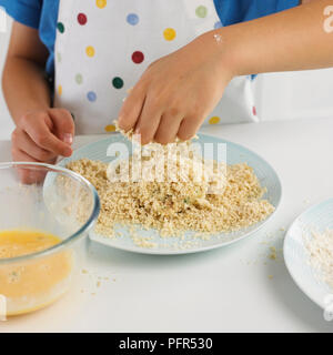 Ragazzo breadcrumbing un fishcake Foto Stock