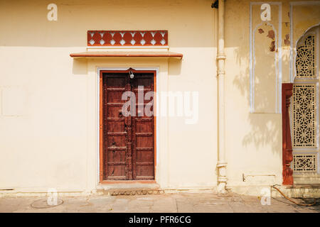 Il vecchio muro giallo e porta di legno al City Palace a Jaipur, India Foto Stock