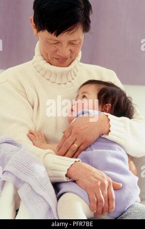 Donna che mantiene undici mesi di età bambino in braccio e vicino al suo corpo Foto Stock